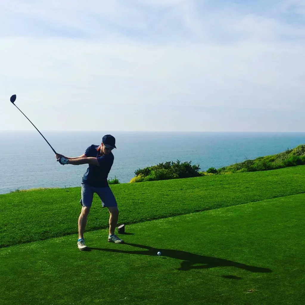 Golfer teeing off on a scenic coastal golf course with ocean views