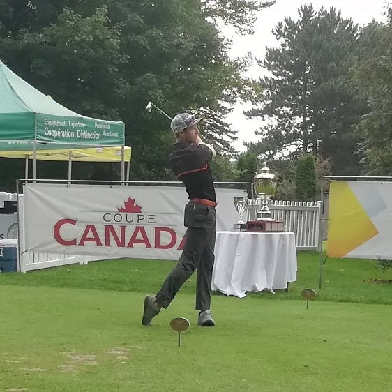 A golfer finishing a powerful swing at a tournament on a lush green course