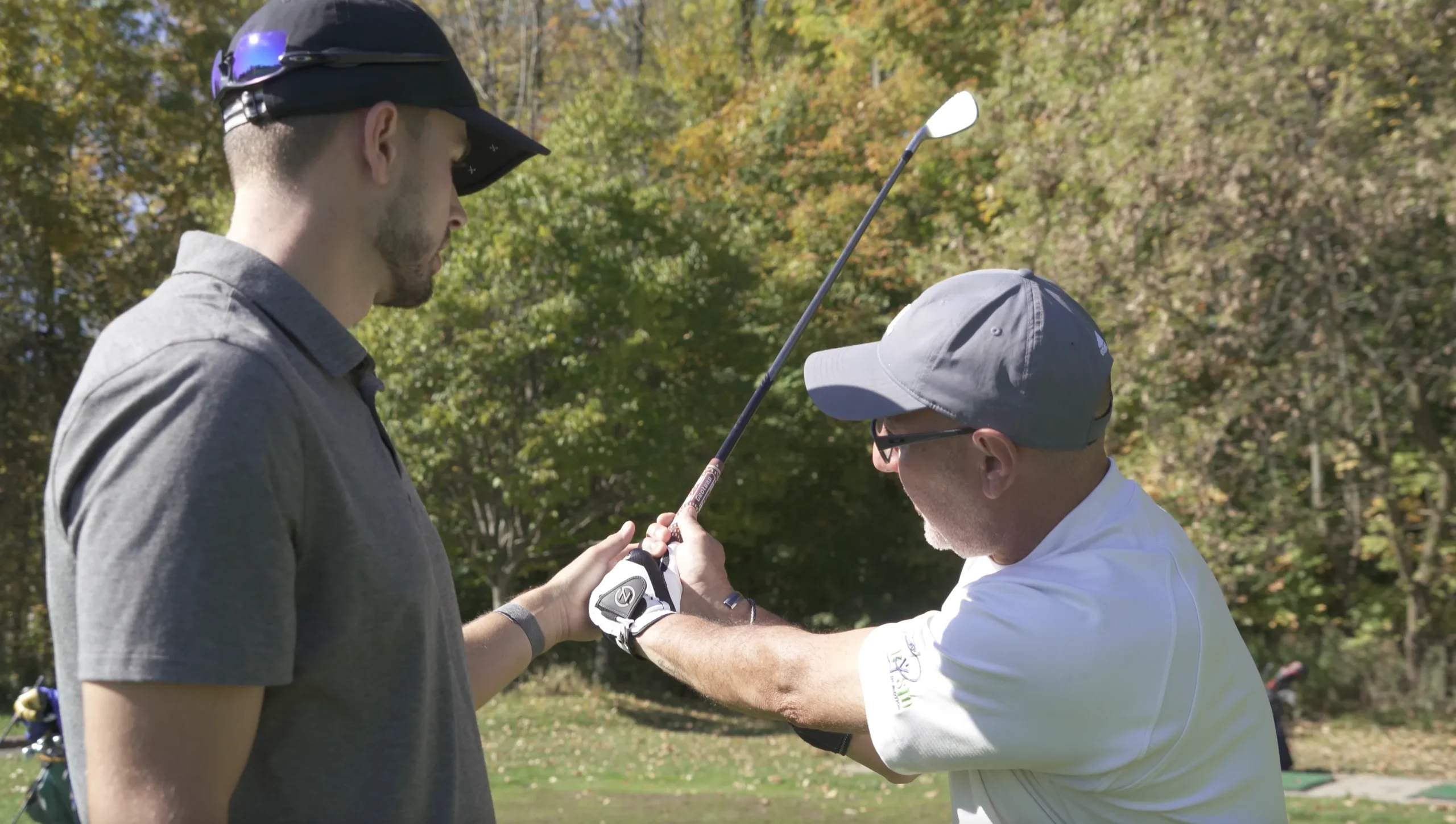 A golf instructor providing a close-up lesson on proper hand grip and club positioning to a student.