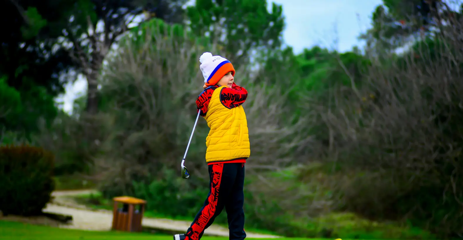 Child golfing in colorful winter attire