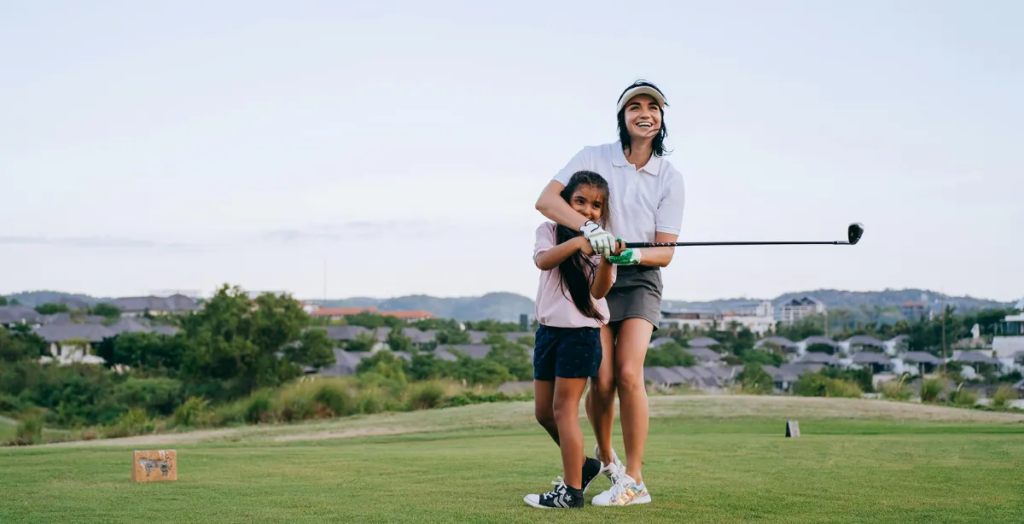 Woman teaching girl to golf