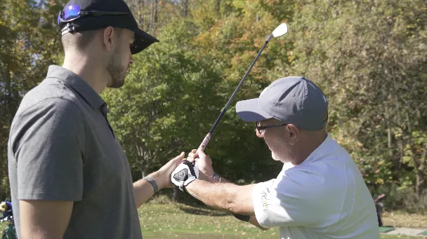 A golf instructor providing a close-up lesson on proper hand grip
